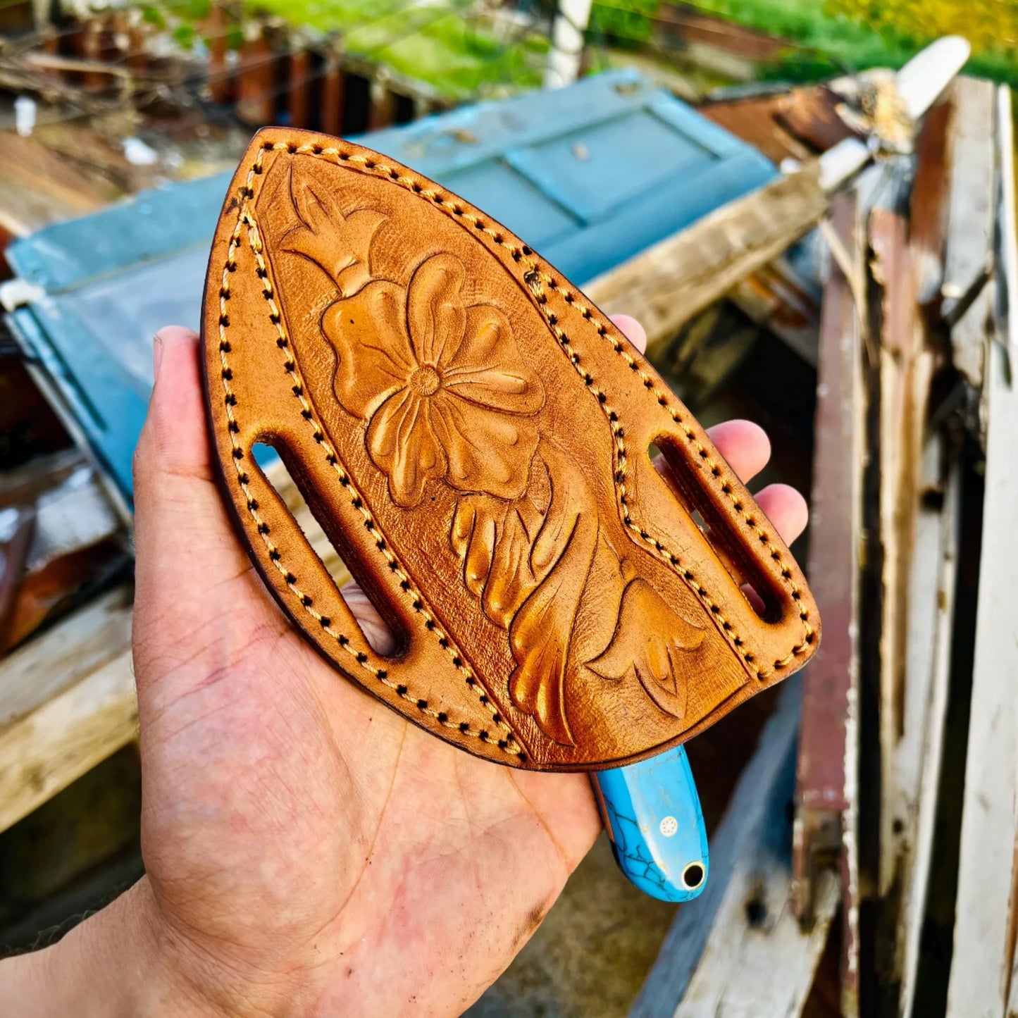 Hand holding a Pancake leather Sheath against a rustic background