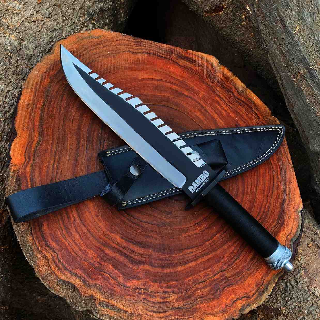 Rambo First Blood Part II replica knife with black leather sheath on a wood round