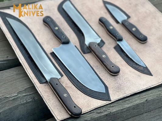 Malika Knives 5-piece kitchen knife set with mixed wenge and black G10 handles displayed on open tan leather knife roll on weathered wood, showing full set layout