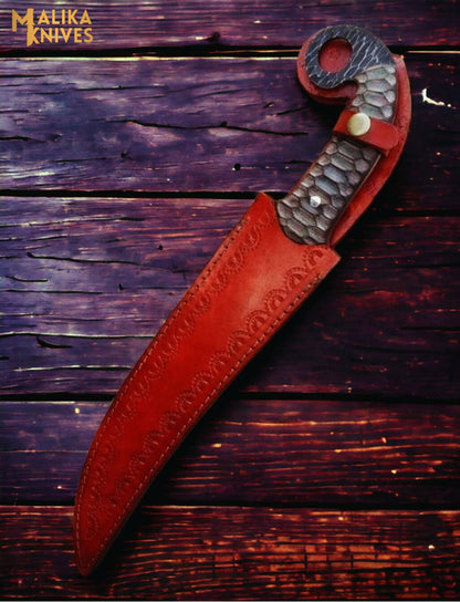 Hand forged Damascus Ringtail Hunting Knife Micarta handle and leather sheath on a wooden surface, brand 'Malika Knives' visible.