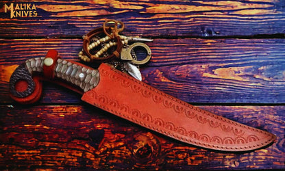 Hand forged Damascus Ringtail Hunting Knife Micarta handle and leather sheath on a wooden surface, brand 'Malika Knives' visible.