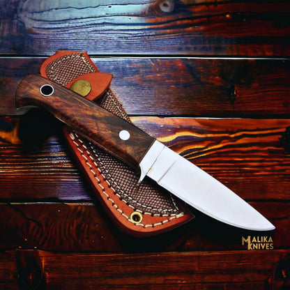 compact handmade d2 hunting knife with rosewood handle and stainless steel guard on wooden background
