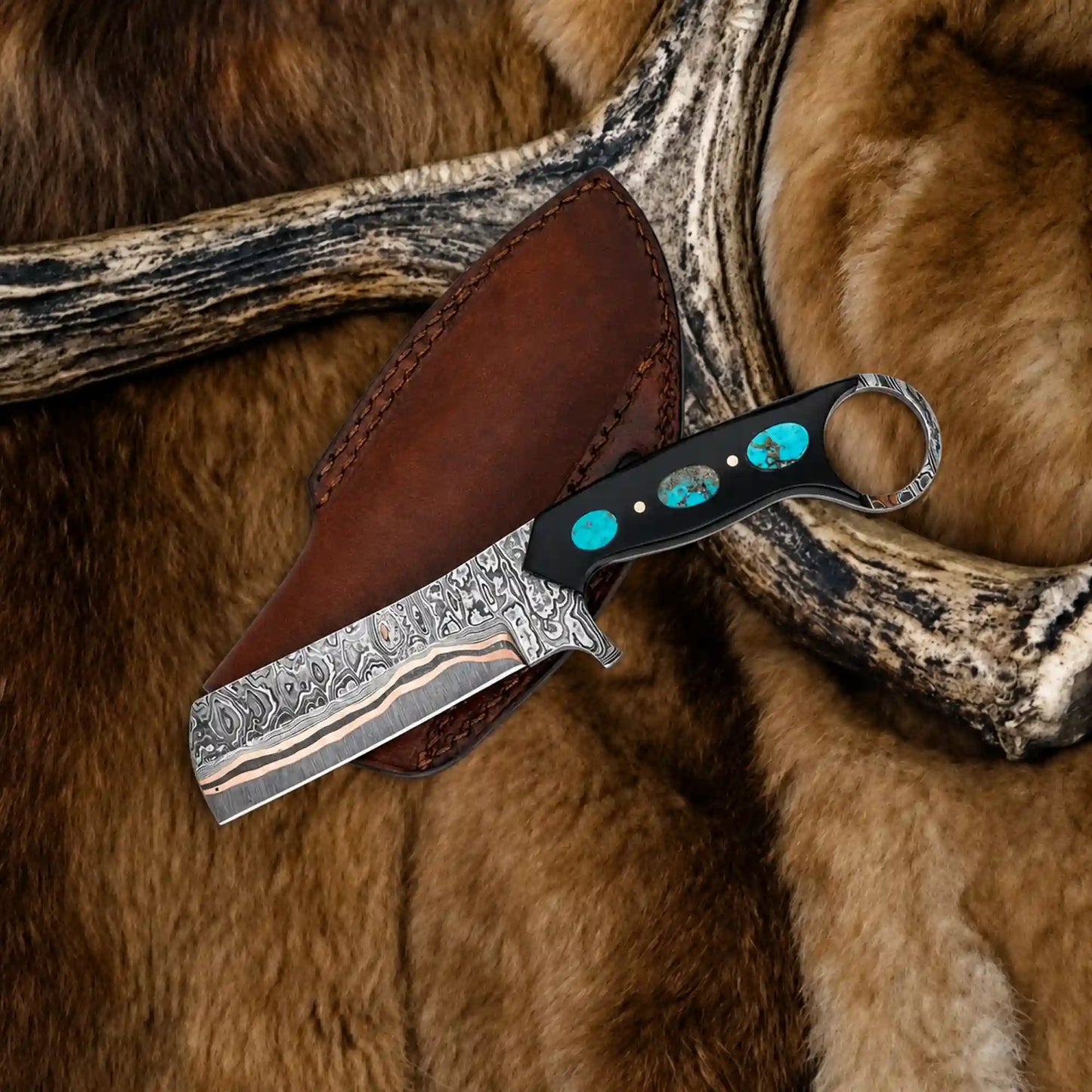 Copper damascus bull cutter knife with turquoise inlaid black resin handle and leather pancake sheath on antler