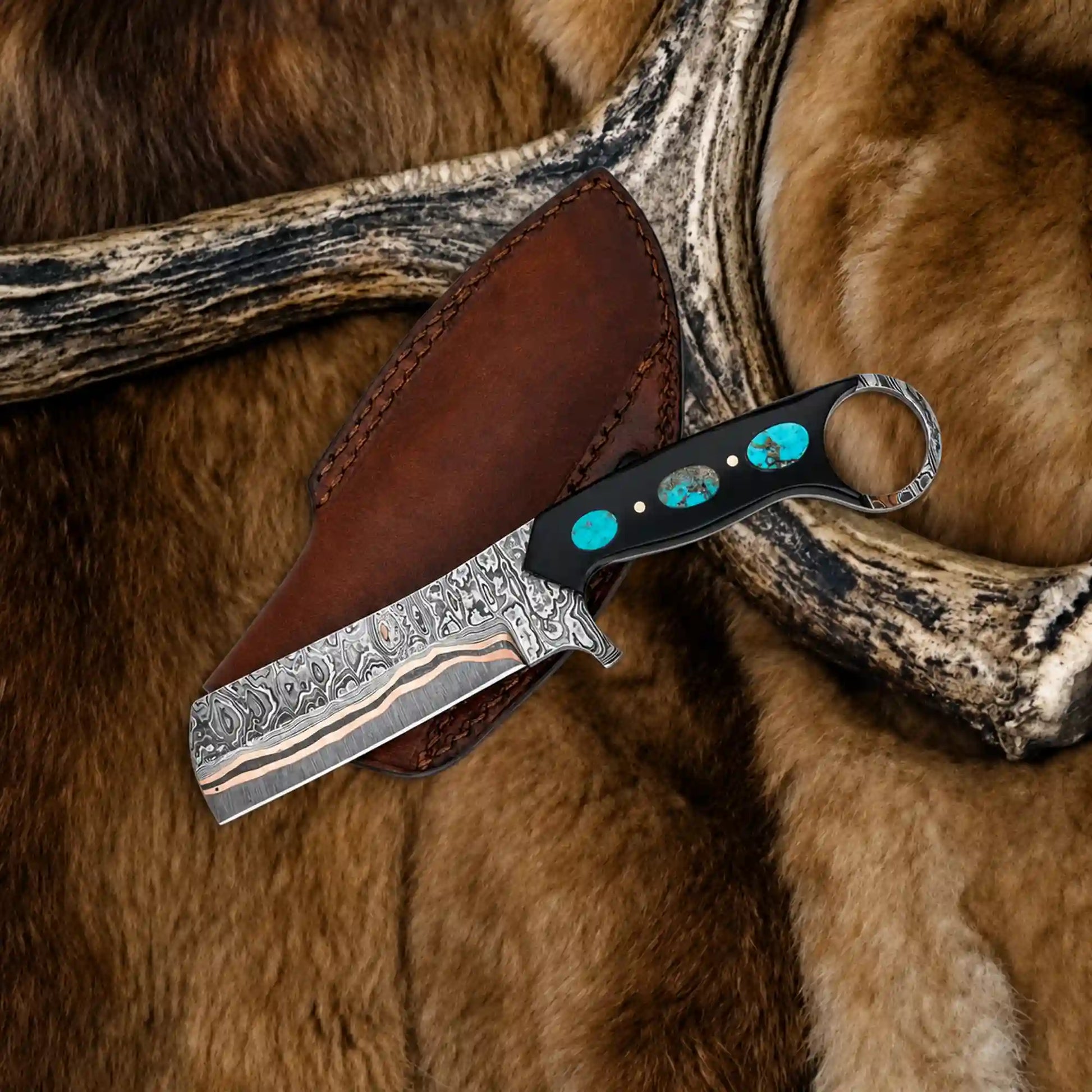 Copper damascus bull cutter knife with turquoise inlaid black resin handle and leather pancake sheath on antler