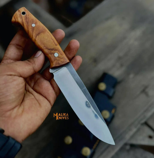 compact d2 bushcraft hunting knife with walnut wood handle held in hand outdoors