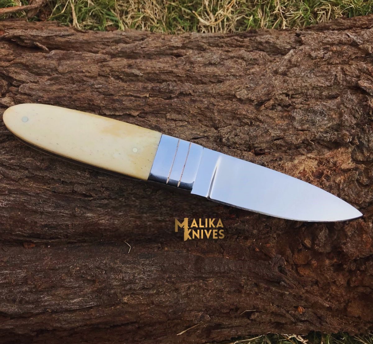 handmade d2 needle point hunting knife with camel bone handle on wooden surface
