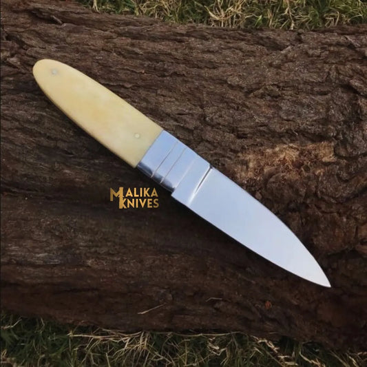 handmade d2 needle point hunting knife with camel bone handle on wooden surface