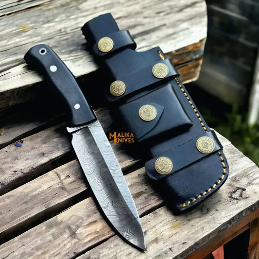 damascus bushcraft hunting knife with micarta handle and leather sheath on wooden surface