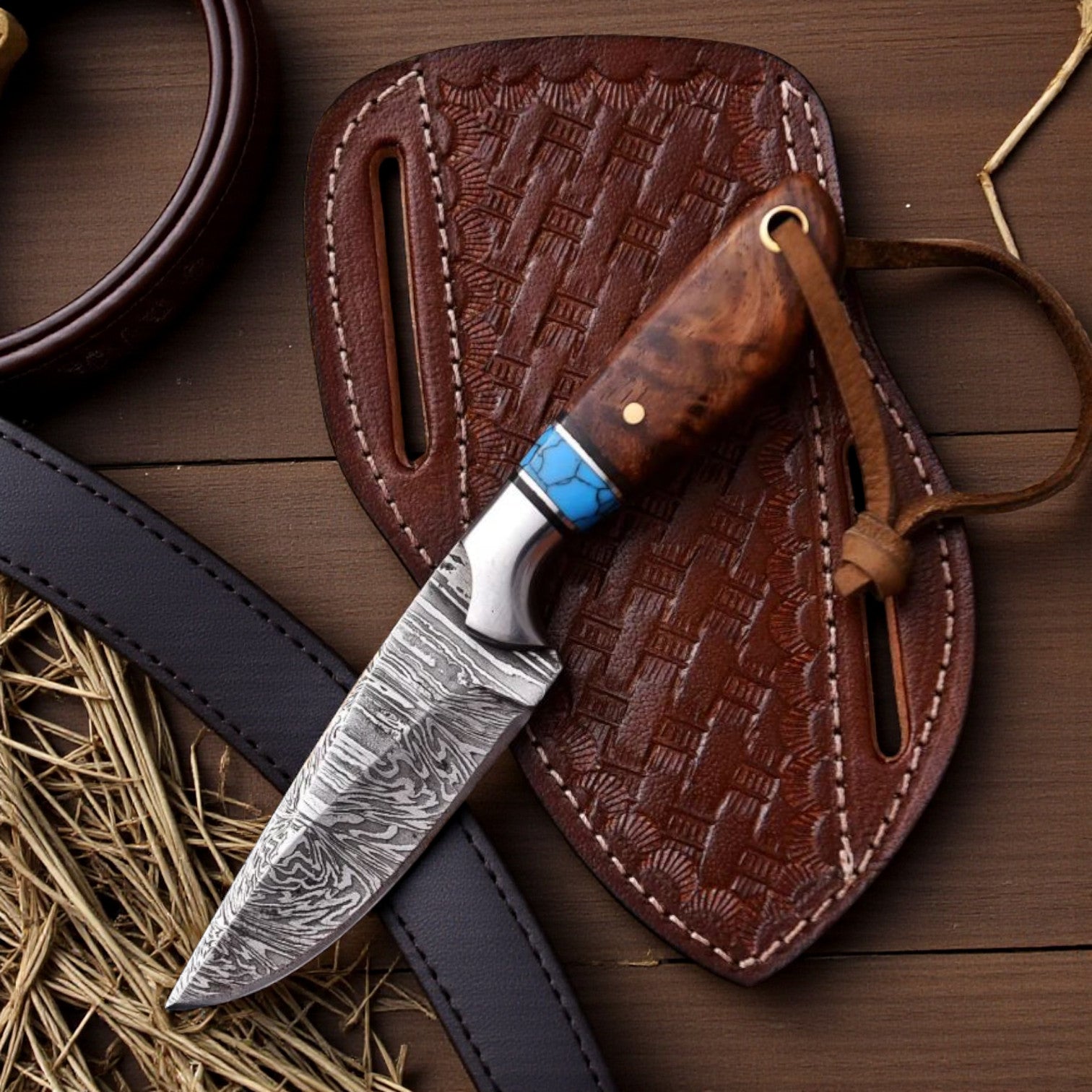 Damascus cowboy hunting knife with rosewood handle and turquoise spacer resting on a basket-tooled pancake leather sheath on a wooden ranch table.