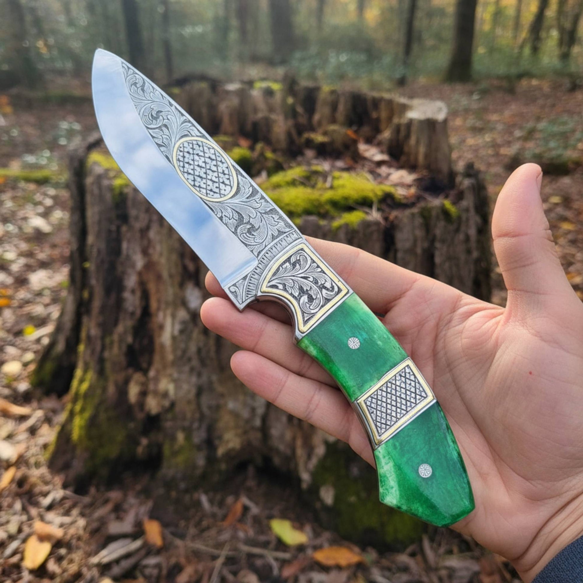 engraved d2 hunting knife with brass inlay and camel bone handle in hand