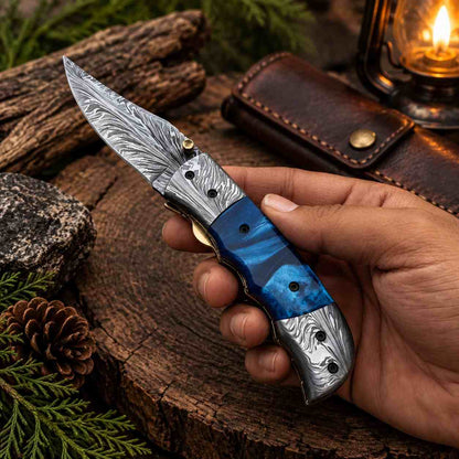 Feather Damascus folding knife with blue pearl resin handle and patterned blade