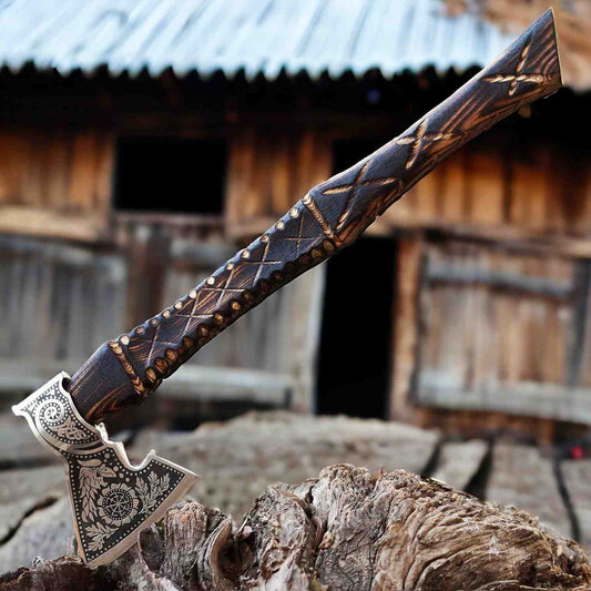 Viking raven axe with Norse sunwheel and oak leaf engraved head resting on a log