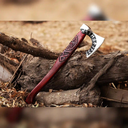 Viking bearded axe with Norse rune engraved head and long red ash handle resting on logs