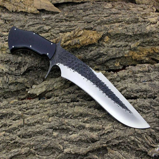 Handforged Bowie Knife with a black G10 handle on a textured wood surface