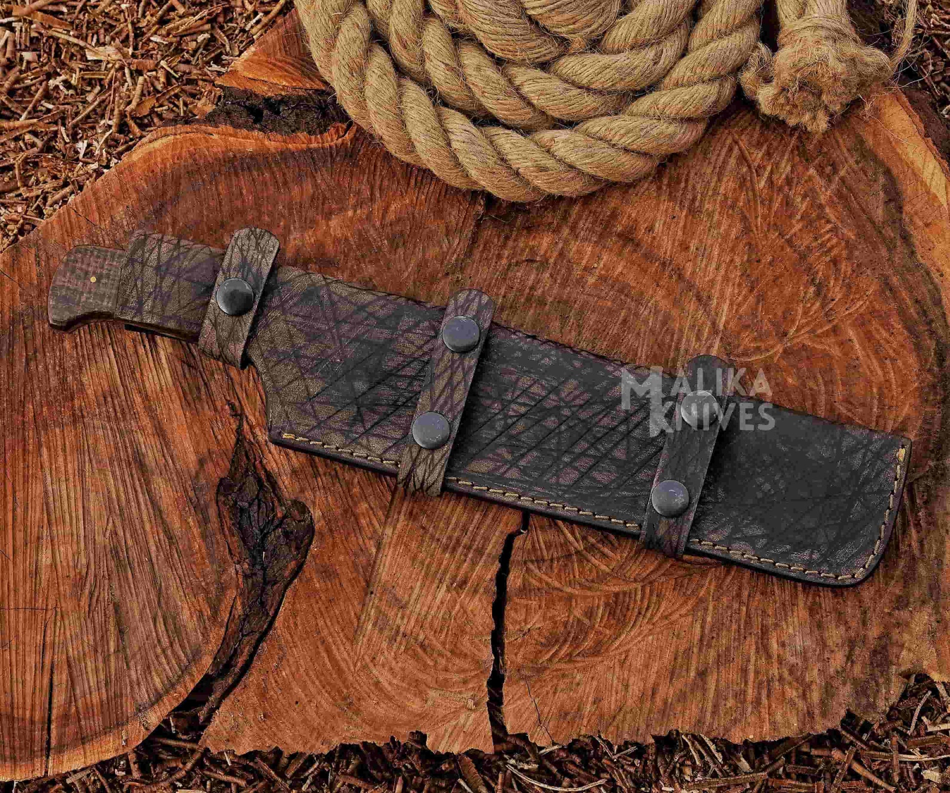 Hunting knife in leather sheath on a wooden surface with 'Malika Knives' branding.