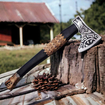 Hand-forged Norse wolf Viking axe with 1075 steel head and carved two-tone ash handle on a wood plank