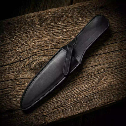 Black leather sheath for a Rambo-style survival bowie knife on weathered wood