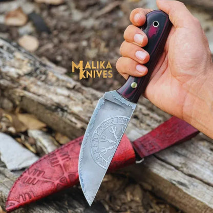 A hand holding a Viking hunting knife with a Micarta handle and a hand engraved cowhide leather sheath in the background.