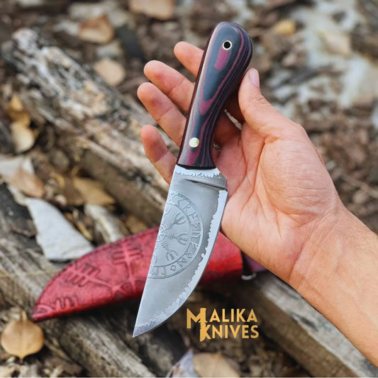 A hand holding a Viking hunting knife with a Micarta handle and a hand-engraved cowhide leather sheath in the background.