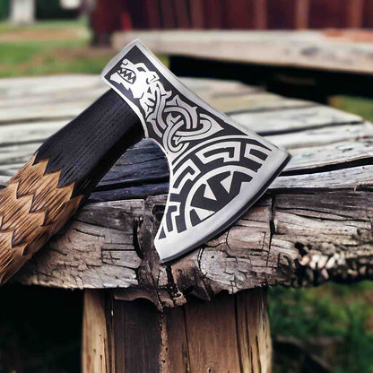 Close-up of Viking wolf axe head showing engraved wolf, Norse knotwork and sunwheel on 1075 steel